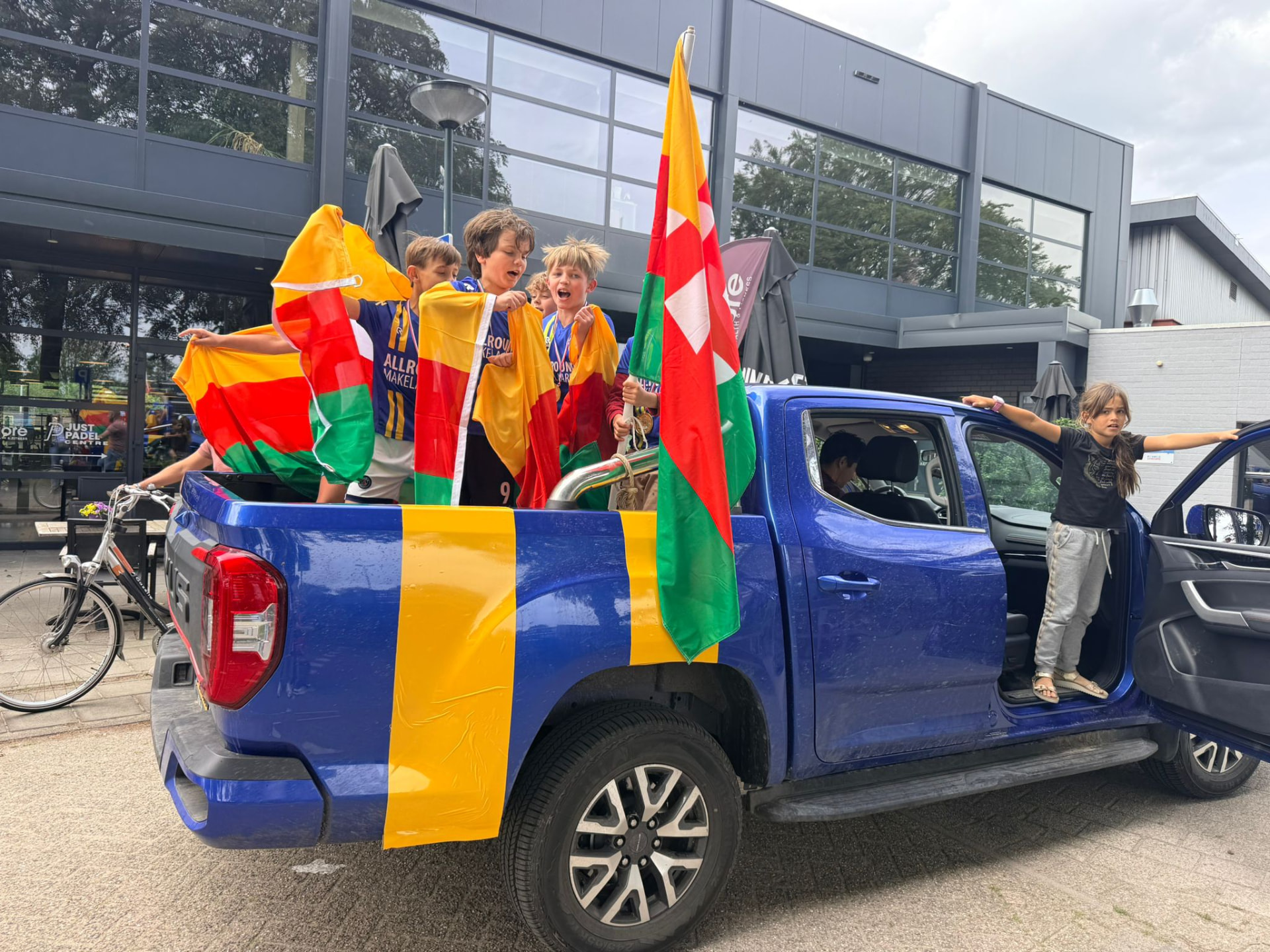 Spelers van Audacia JO-08 met clubvlaggen tijdens het huldigingsrondje in de Audacia pick-up